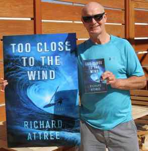 Richard Attree in 2019, aged 66, with a large poster of his novel, 'Too Close to the Wind'.